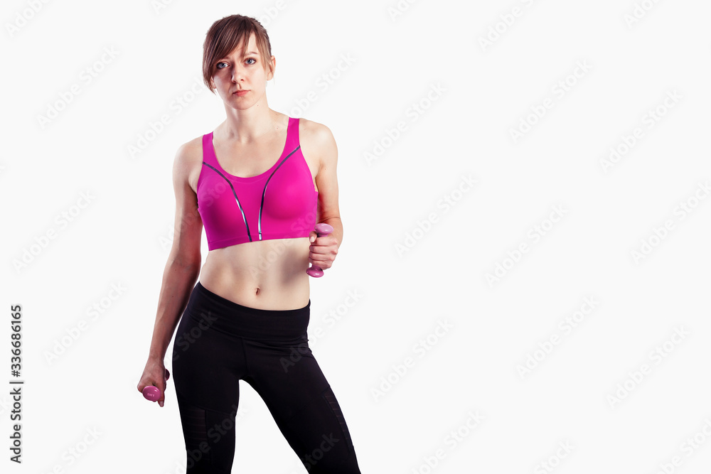 Sporty woman does the exercises with dumbbells on gray background. Photo of muscular woman in sportswear at studio Sporty woman does the exercises with dumbbells on gray background. Photo of muscular woman in sportswear at studio