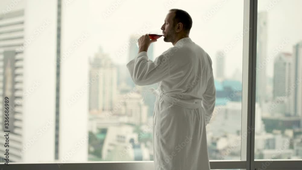 Happy man in bathrobe drinking wine and admire view from window, 4K
Happy man in bathrobe drinking wine and admire view from window, 4K