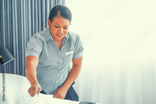 African maid making bed in hotel room. Staff Maid Making Bed. African housekeeper making bed.