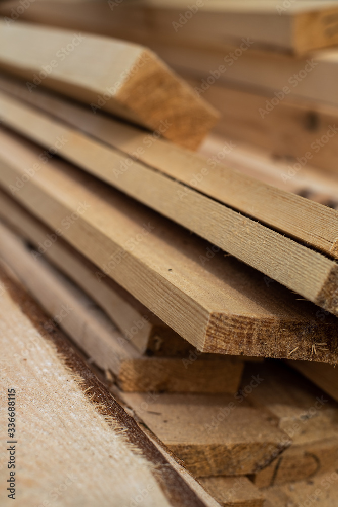 Stack of natural brown uneven rough wooden boards on building site. Industrial timber for carpentry, building