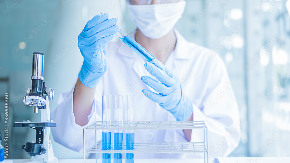 Fototapeta premium Medical or scientific researcher or man doctor looking at a test tube of clear solution in a laboratory