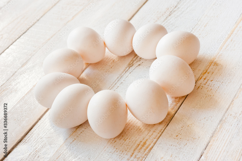 White chicken eggs lying on a white painted wooden surface. Background for livestock products. White chicken eggs lying on a white painted wooden surface. Background for livestock products.