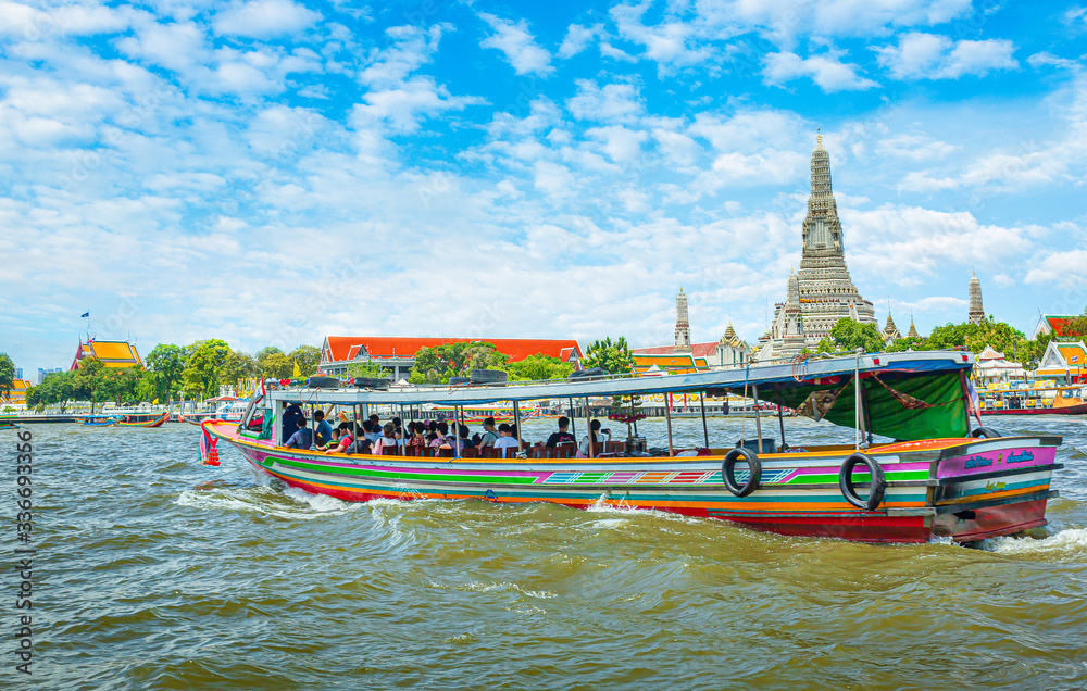 Obraz premium View over river Chao Phraya from boat back to temple Wat Arun, eldest temple in Bangkok. In foreground is speed longboat passing. Behind are tour boats and ferries.