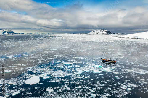 aerial view to sail yacht thar rides through floating icebergs in strait in Antarctica