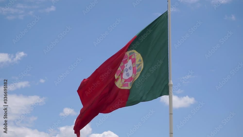 Static close-up shot of the Portugal flag on blue sky daylight with some clouds - Center framed