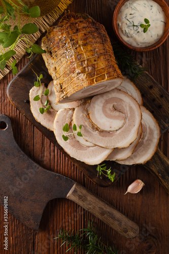 Whole bacon roulade. Served in sliced meat with white sauce. Top view.