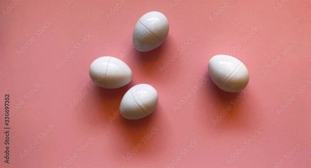 Eggs line up in a dance on a pale pink background. Flat lay easter concept. Stop motion animation.