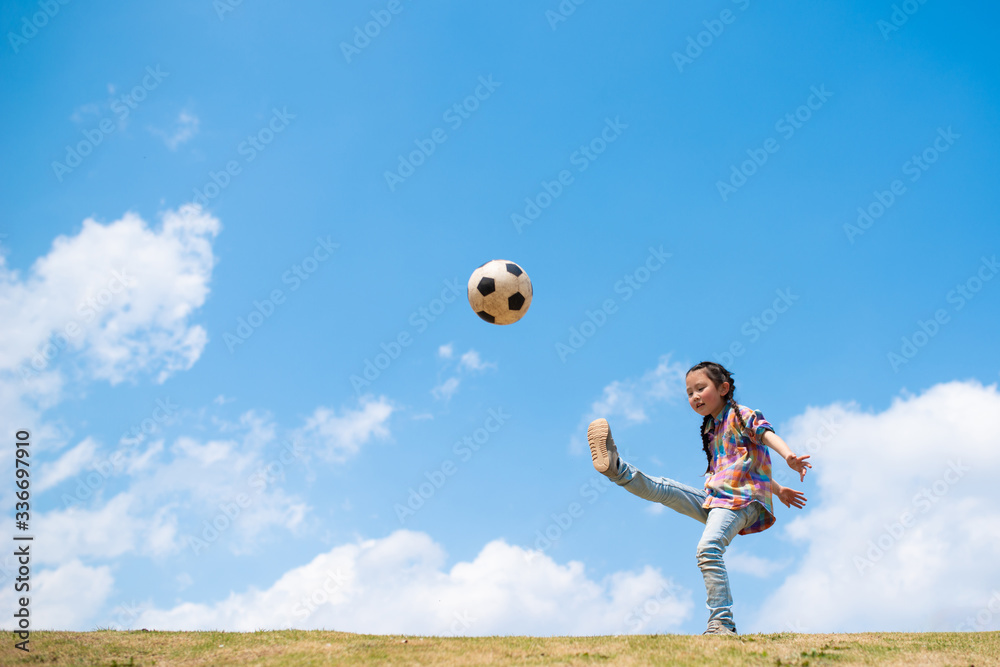 青空の下でサッカーボールを蹴る子供 Stock Photo Adobe Stock