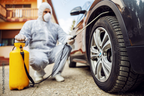 Man in protective suit with mask disinfecting car tires, prevent infection of Covid-19 virus coronavirus,contamination of germs or bacteria. Infection prevention and control of © dusanpetkovic1