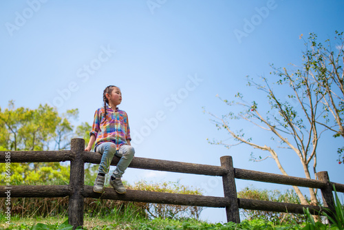 公園の柵に座って遠くを見る女の子