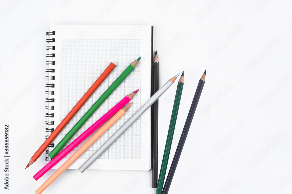 Some different color wood pencil crayons scattered across and on top of a white diary Some different color wood pencil crayons scattered across and on top of a white diary