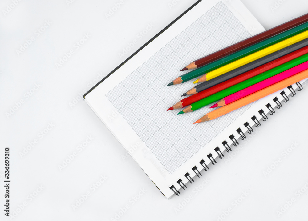 Some different colored pencil crayons scattered on top of an open white paper diary Some different colored pencil crayons scattered on top of an open white paper diary