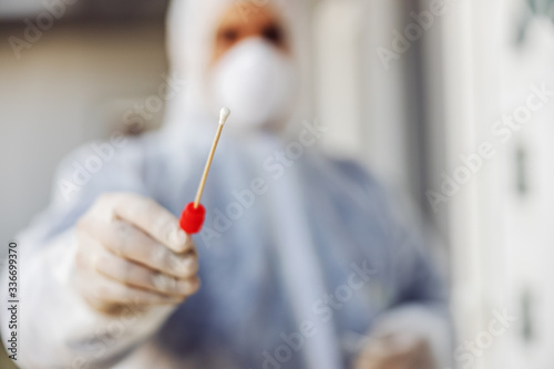 Fotografia Man in protective suit with mask holding sample buccal cotton swab and test tube ready to collect DNA from the cells