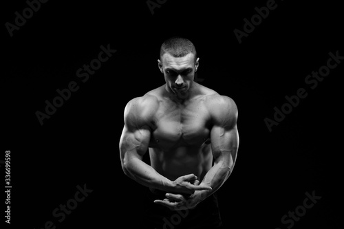Muscular model sports young man in jeans showing his press on a black background. Fashion portrait of sporty healthy strong muscle guy. Sexy torso. Black and white photography 