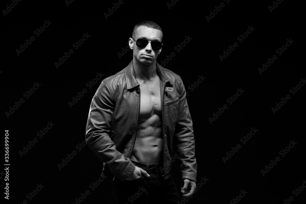 Sexy torso.  Fashion portrait of sporty healthy strong muscle guy.  Muscular model sports young man in jeans showing his press on a black background. Black and white photography
