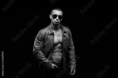 Sexy torso.  Fashion portrait of sporty healthy strong muscle guy.  Muscular model sports young man in jeans showing his press on a black background. Black and white photography

