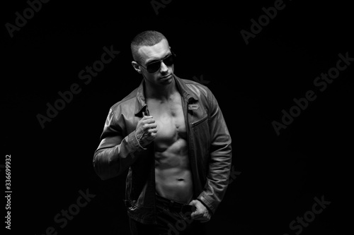 Sexy torso. Fashion portrait of sporty healthy strong muscle guy. Muscular model sports young man in jeans showing his press on a black background. Black and white photography 