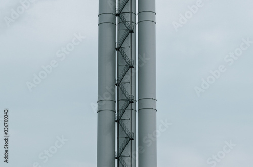The chimney of a large industrial plant. Tall chimney with a long staircase
