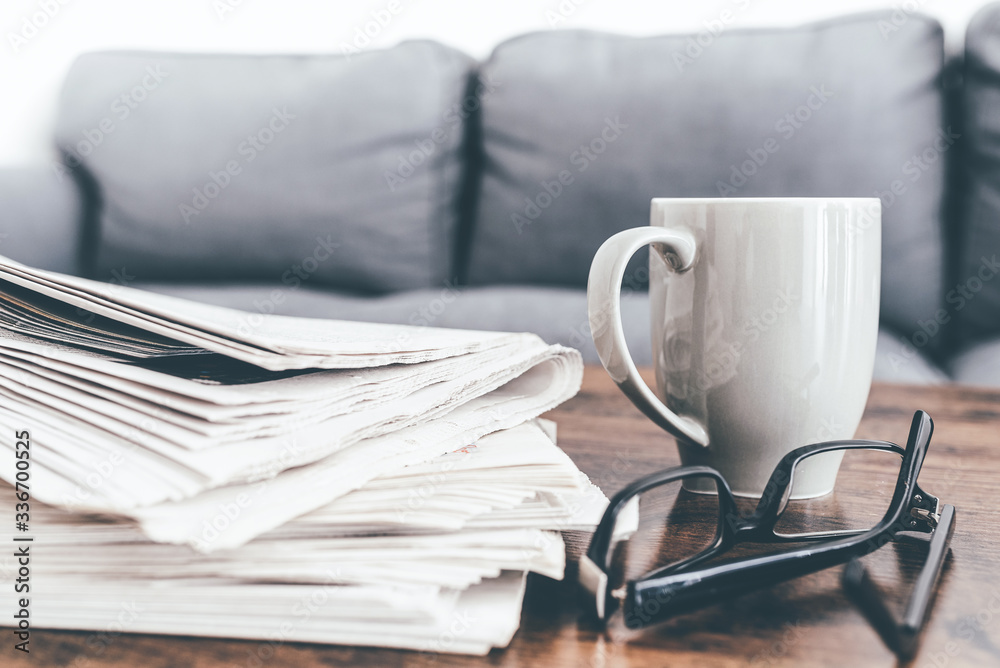 close-up shot of stack of newspapers, coffee mug and glasses on living room table. close-up shot of stack of newspapers, coffee mug and glasses on living room table.