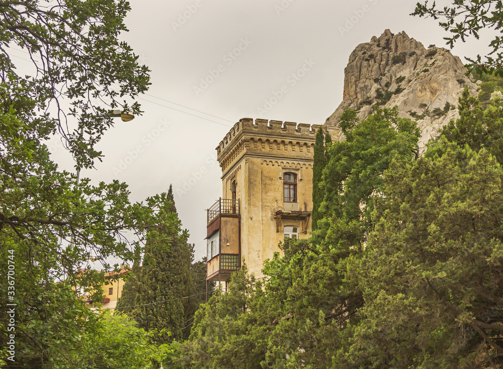 Fototapeta premium Old residential buildings surrounded by green trees on the background of mount Cat in Simeiz.Crimea.
