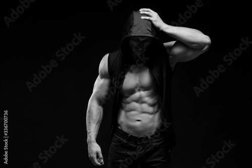 Muscular bodybuilder on a dark background. Man feeling a pain in his head. Black and white photography
