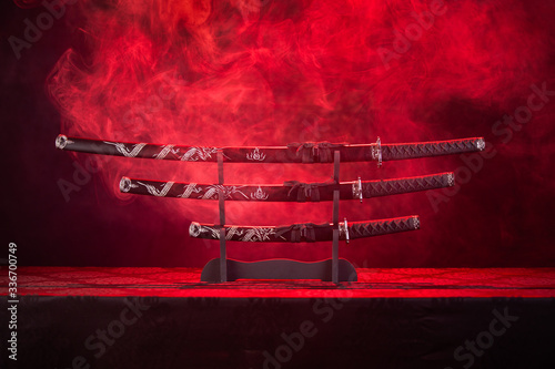 Photography Three swords on stand, red smoke behind