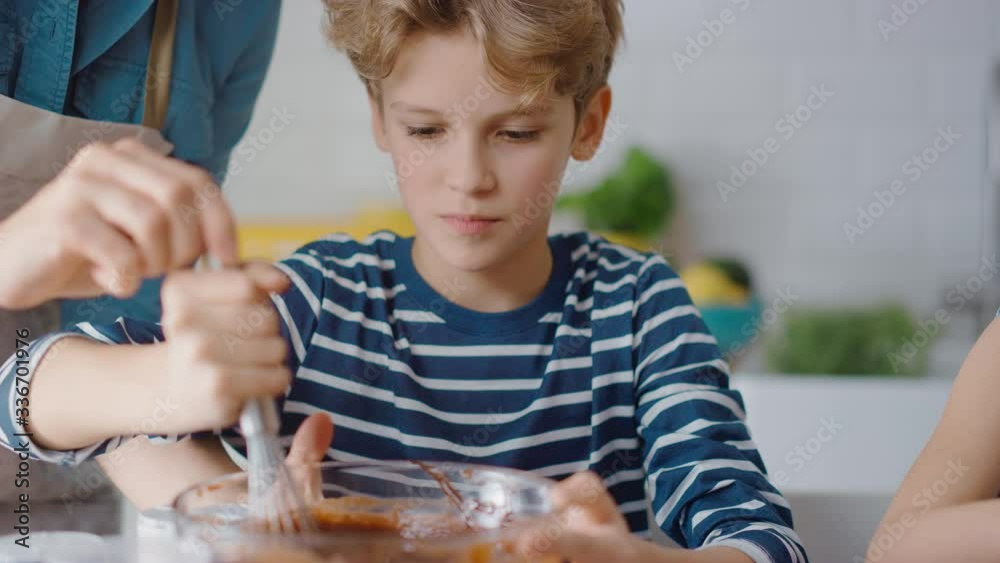 
In the Kitchen: Portrait of the Cute Smart Boy Mixing Flour and Water to Create Dough for Cupcakes. Family Cooking Muffins Together. Adorable Children Helping their Caring Parents