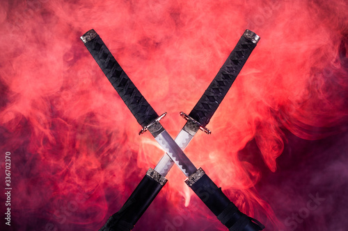 Partially drawn blades of two katanas in red smoke