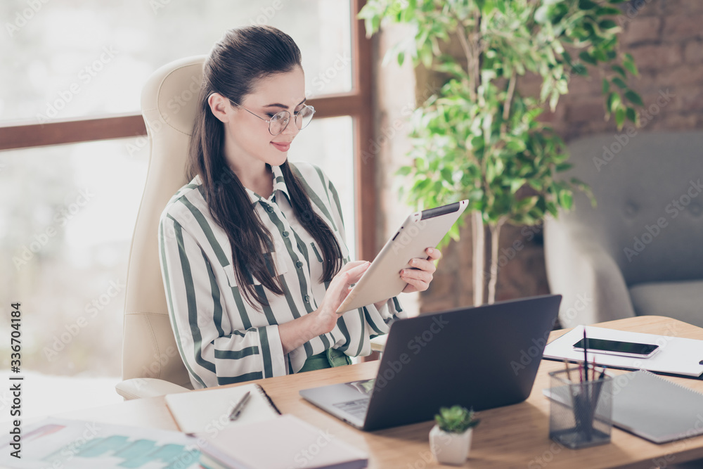 Portrait of focused concentrated business woman girl company owner use tablet search start up development seminar wear striped shirt sit table desk in workplace workstation Portrait of focused concentrated business woman girl company owner use tablet search start up development seminar wear striped shirt sit table desk in workplace workstation