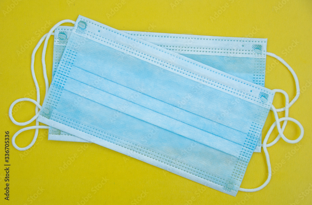 Medical mask on yellow background, flat lay, top view. Protection against virus, coronavirus, flu, colds Medical mask on yellow background, flat lay, top view. Protection against virus, coronavirus, flu, colds