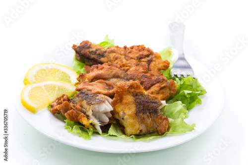 fried hake fish in batter with lettuce and lemon in a plate