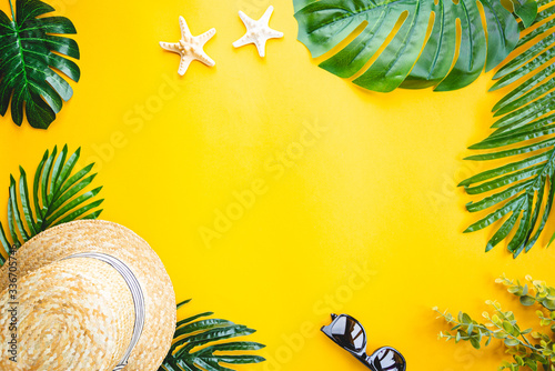 Straw beach hat and sun glasses top view on yellow background, summer flat lay