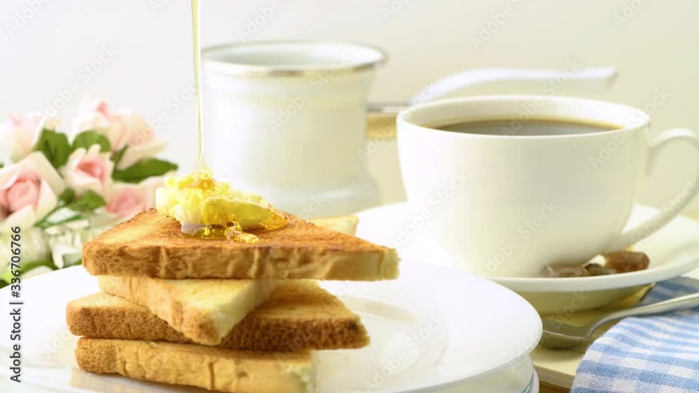 The concept of a healthy nutritious breakfast. A serving of toasted wheat bread toast with butter and honey and a cup of hot coffee. Close-up. Selective focus. 4K UHD video 3840x2160 The concept of a healthy nutritious breakfast. A serving of toasted wheat bread toast with butter and honey and a cup of hot coffee. Close-up. Selective focus. 4K UHD video 3840x2160
