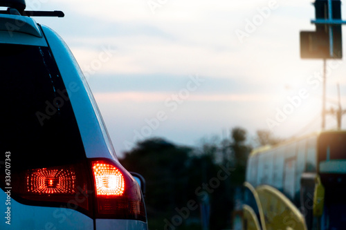 Backside of family car white color with open brake light on the road evering time.