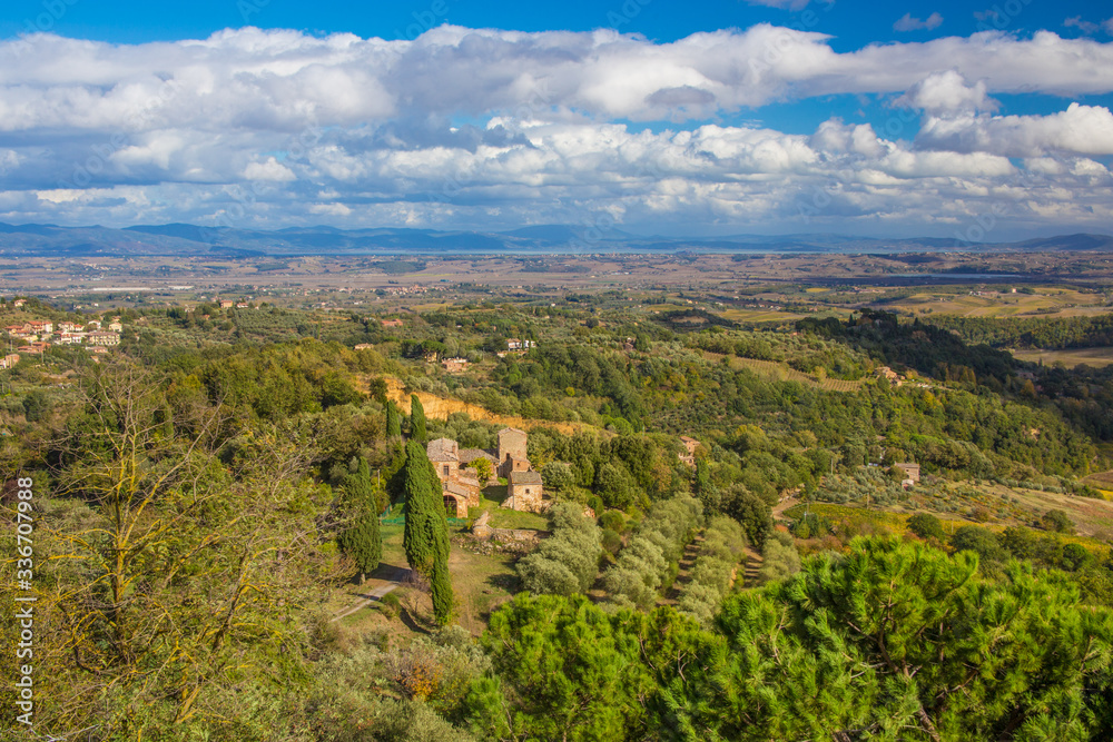 Autumn landscape in Tuscany, Italy. Beautiful view with a house in the D'Orcia Valley, surrounded by green trees.