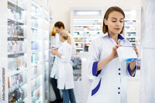 Attentive female pharmacist reading the composition of the drug.