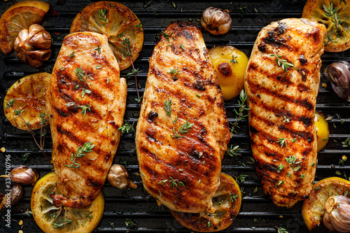 Grilled chicken breasts with thyme, garlic and lemon slices on a grill pan, top view photo