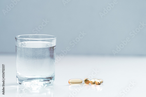 Dramatic medical mood - glass of drinking water and pills (tablets or drugs) on the table. Close up