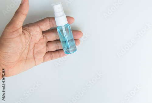 Blurred blue alcohol spray bottle on hand on white background