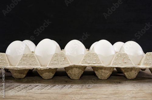 white chicken eggs in a tray on a wooden table. Side view.