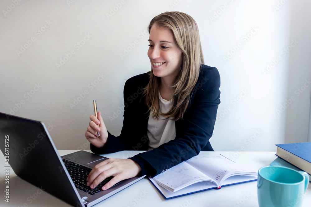 Smiling young female entrepreneur sitting at home working with her laptop Smiling young female entrepreneur sitting at home working with her laptop