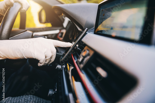 Man with protective mask and gloves driving a car typing at mobile phone smartphone. Infection prevention and control of epidemic. World pandemic. Stay safe. © dusanpetkovic1