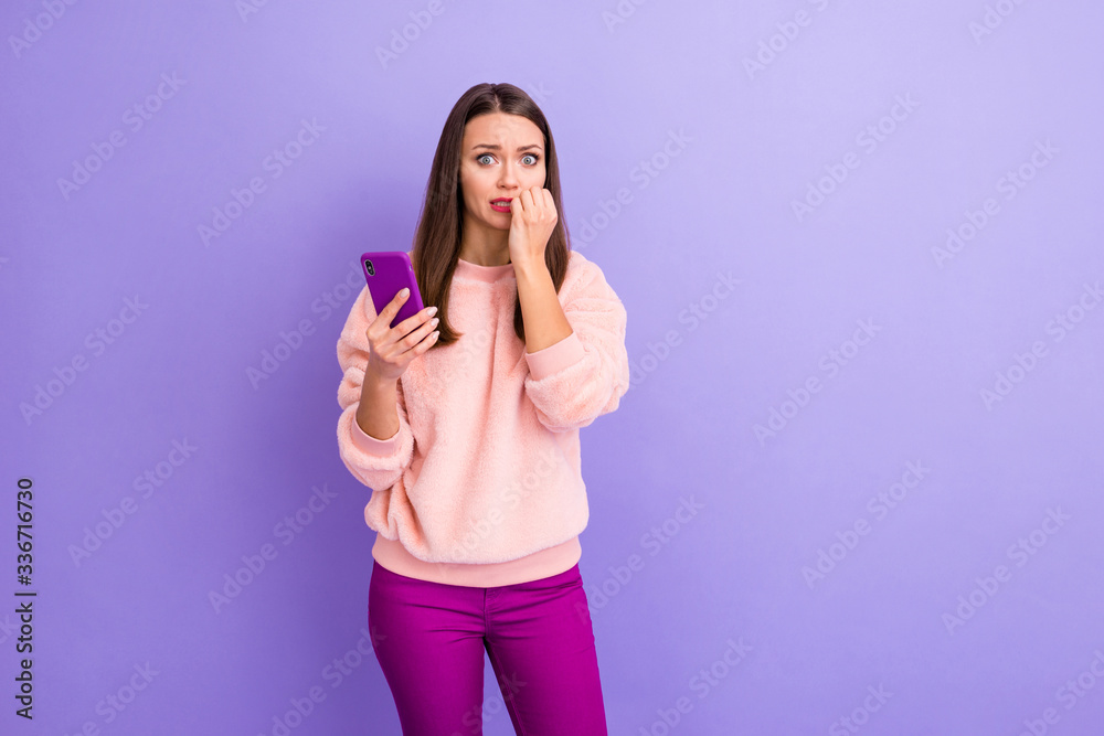 Photo of pretty blogger lady hold telephone not believe unfollowers number biting fingers fear eyes wear casual fur pullover trousers isolated purple color background Photo of pretty blogger lady hold telephone not believe unfollowers number biting fingers fear eyes wear casual fur pullover trousers isolated purple color background