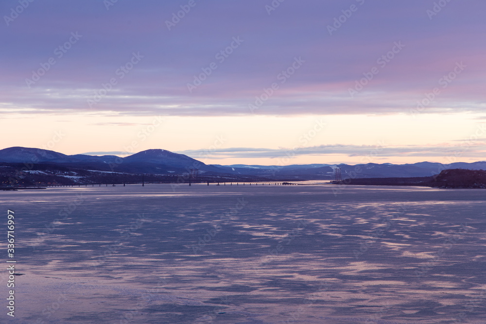 East view of the St. Lawrence River, with the Island of Orleans Bridge and Beauport Coast in the background seen during an early morning blue hour, Quebec City, Quebec, Canada