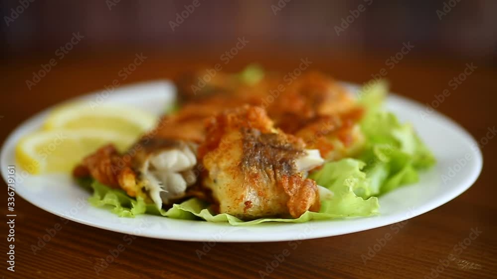 fried hake fish in batter with lettuce and lemon in a plate on a wooden table fried hake fish in batter with lettuce and lemon in a plate on a wooden table