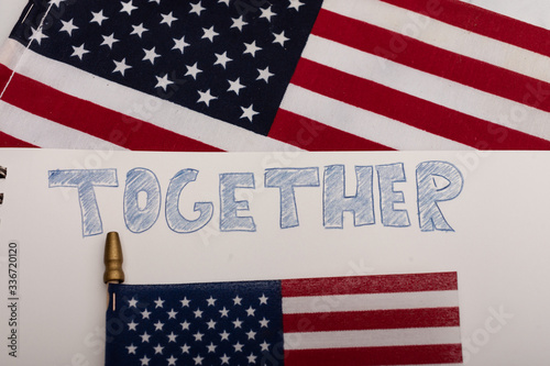 The word together hand-sketched on white paper with American flags in the background USA coming together 