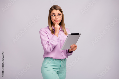 Portrait of minded pensive manager girl work tablet have difficult decisions solution think thoughts look copyspace touch hand chin wear violet mint color pants isolated grey color background
