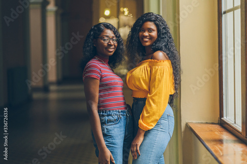 Portrait of two female nigerian students meets in dark university interior. African woman in bright cilor clothes photo