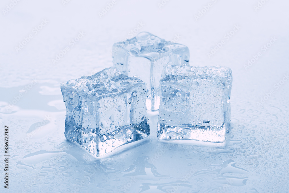 several melted ice cubes with drops on a light background with blue tinting several melted ice cubes with drops on a light background with blue tinting