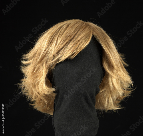 Blond hair wig isolated on black background.